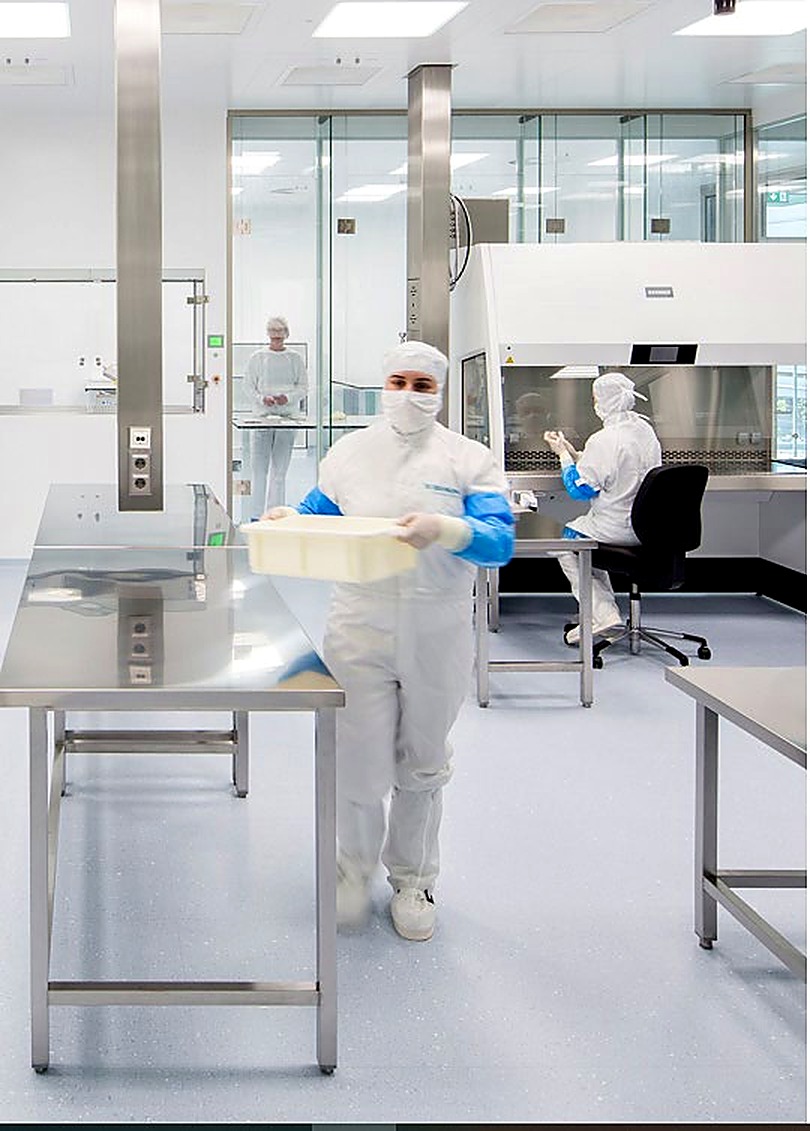 Cleanroom technician in full protective suit working at a sterile workstation